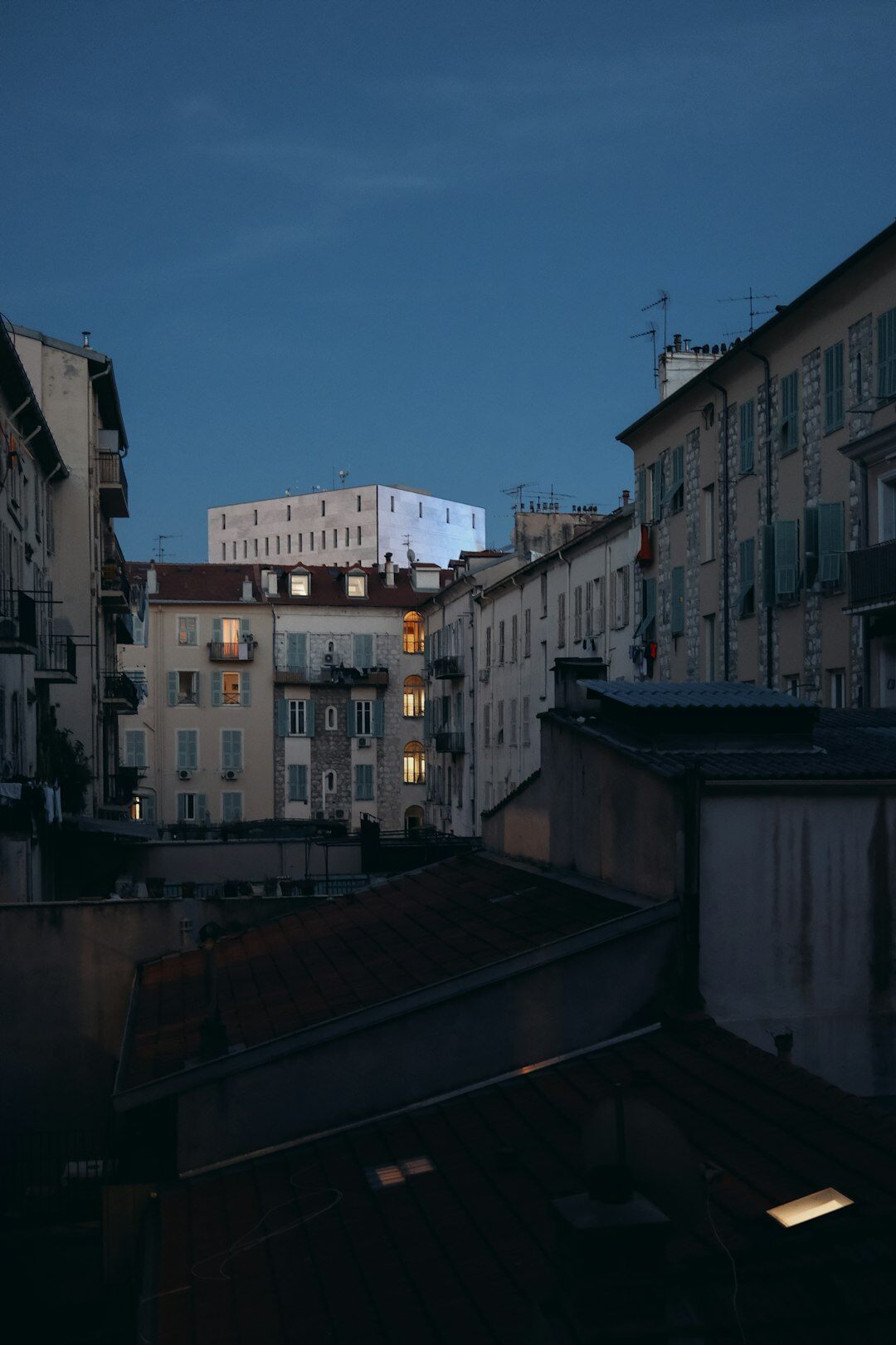 Rainy city rooftops at dusk with warm lit windows